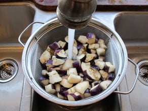 Rinsing salt from eggplant in a colander.