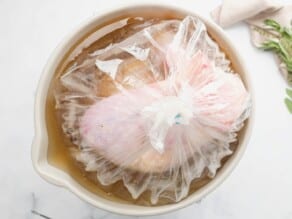 Overhead shot of an uncooked turkey in a bag filled with brine, sitting in a stock pot.