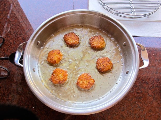 Frying latkes in oil in a skillet.