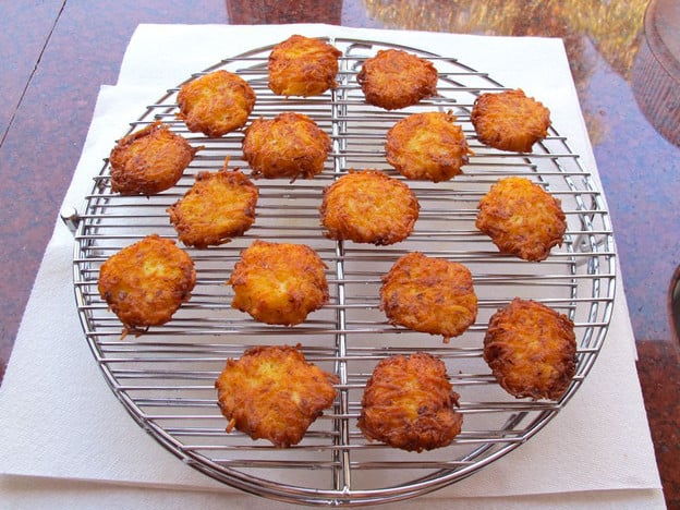 Latkes draining on a cooling rack over paper towels.