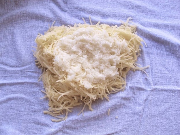 Drained potatoes and onions in a tea towel.