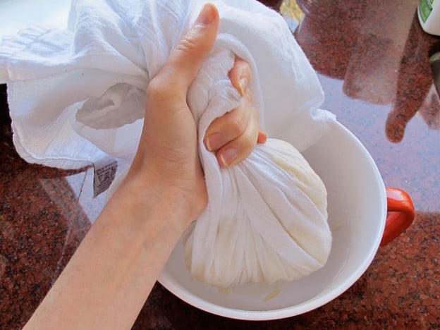 Squeezing water out of potatoes in a tea towel.