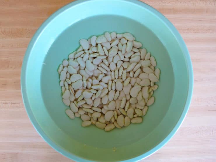 Dried butter beans soaking in a bowl of water.