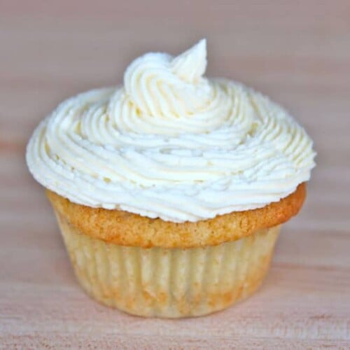 A coconut buttercream frosting cupcake with a white swirl on top