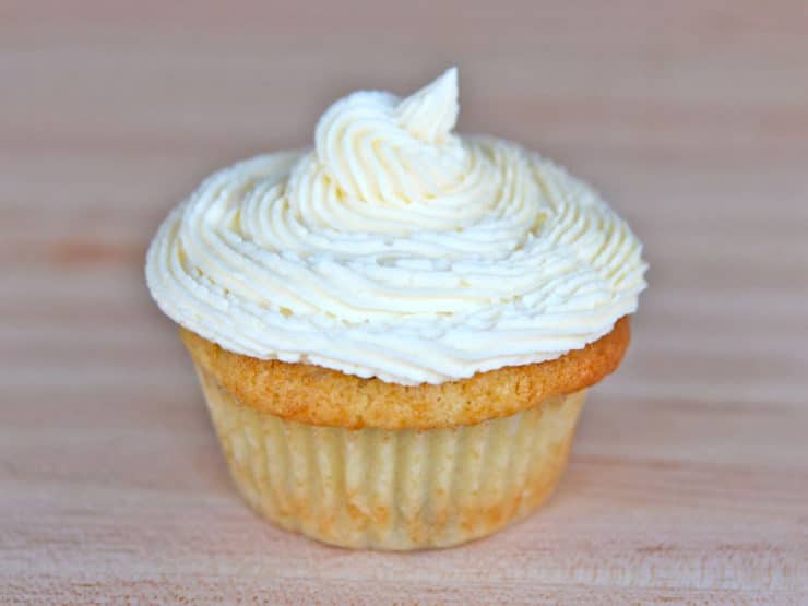 A coconut buttercream frosting cupcake with a white swirl on top