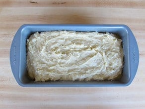 Coconut cake batter spread into a loaf pan.