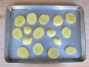 Sliced potatoes on a baking sheet.