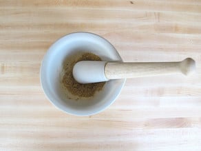 Crushing spices with a mortar and pestle.