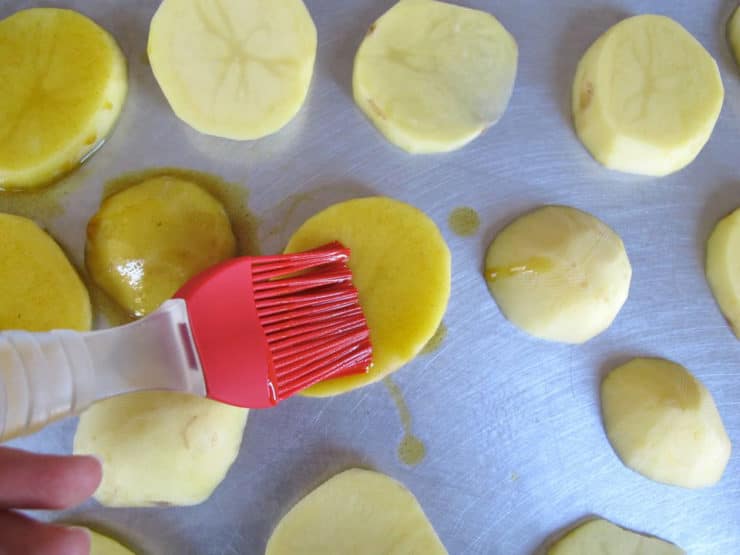 Brushing olive oil on potato slices.