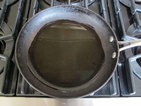 Heating olive oil to smoking in a nonstick skillet.