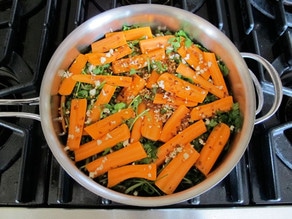 Simmering carrots and spices in a skillet of water.