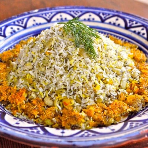 Iranian Baghali Polo basmati rice dish mixed with beans and dills served on a blue designed plate