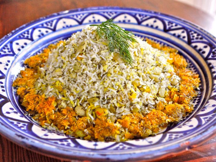 Iranian Baghali Polo basmati rice dish mixed with beans and dills served on a blue designed plate