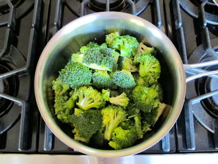 Steaming broccoli florets in a saucepan.