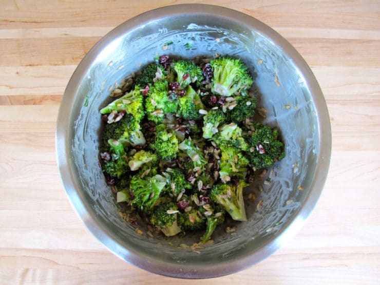 Broccoli tossed with dressing in a large bowl.