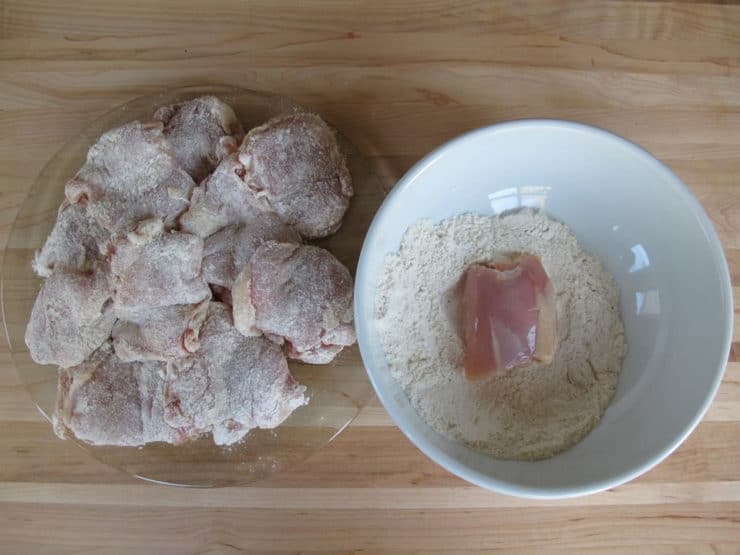 Dredging chicken thighs in seasoned flour.