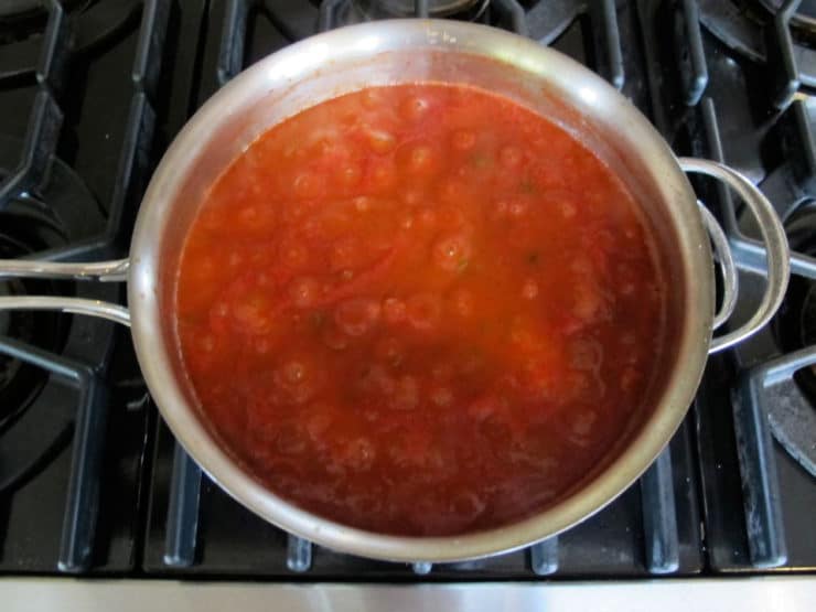 Slowly heating a saucepan of tomato sauce.
