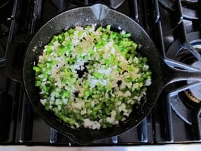 Diced peppers and onions in a skillet.