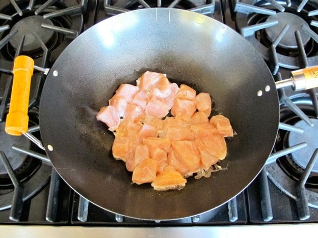 Cooking chicken pieces in a wok.