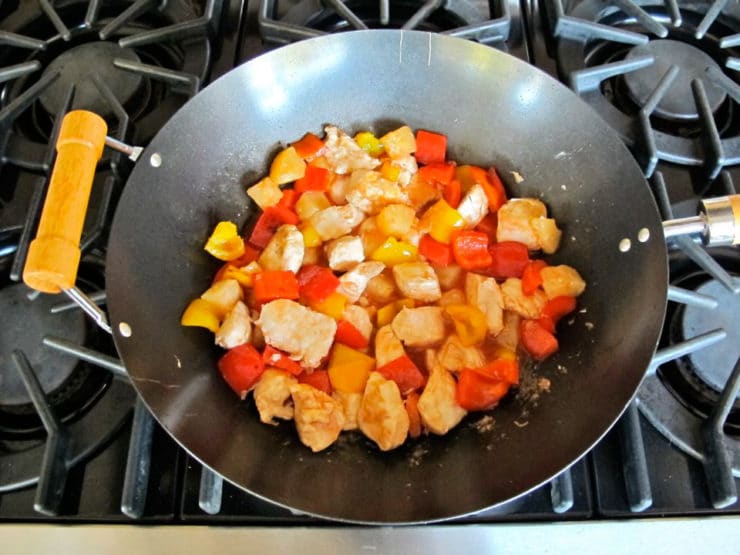 Bell peppers and chicken in a wok.
