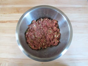 Use hands to combine meatloaf ingredients in a bowl.