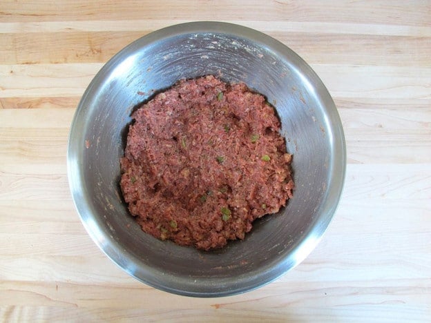 Mix beaten eggs into meatloaf using hands.