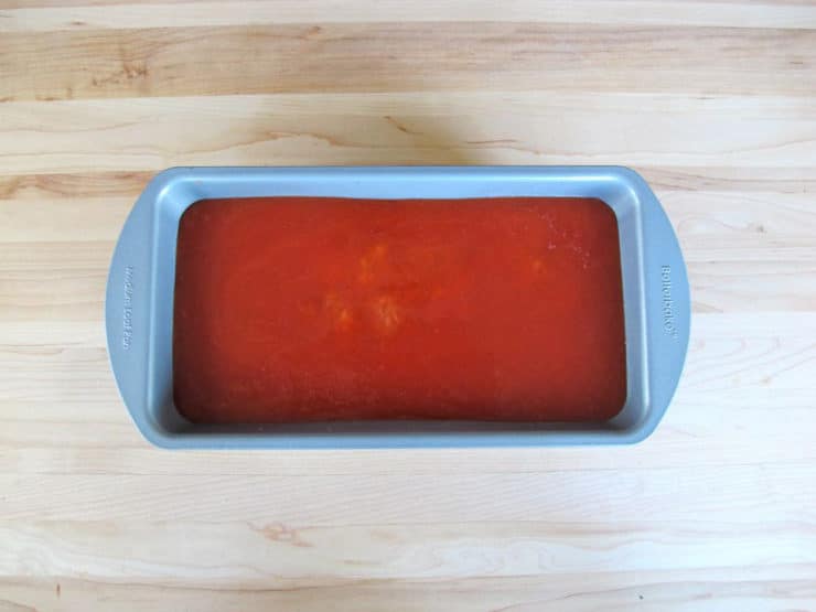 Tomato juice poured over meatloaf in loaf pan.