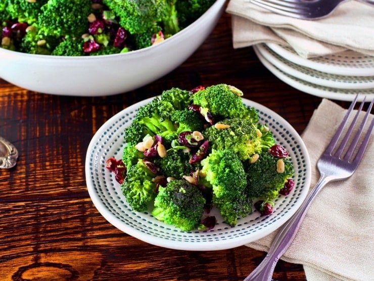 A colorful broccoli craisin salad made with broccoli florets, craisins, and a creamy dressing, served in a white bowl