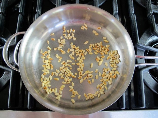 Dry toasting pine nuts in a skillet.