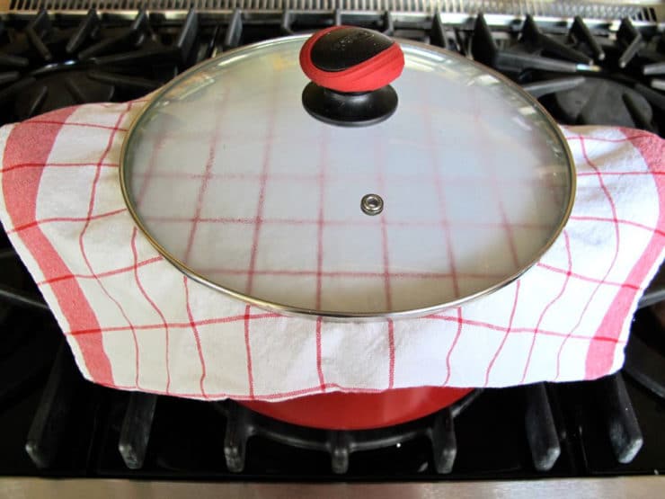 Stockpot with a kitchen towel sandwiched between the pot and lid.