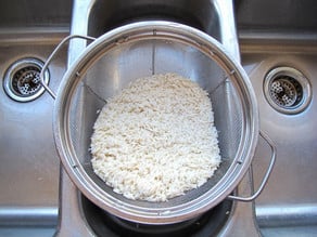 Draining soaked rice in a colander.