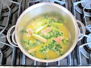 Chicken and lemongrass simmering in a pot of stock.
