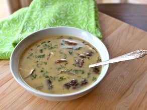 Thai Style Coconut Chicken Soup Main served on a white plate with a spoon served on top of a chopping board