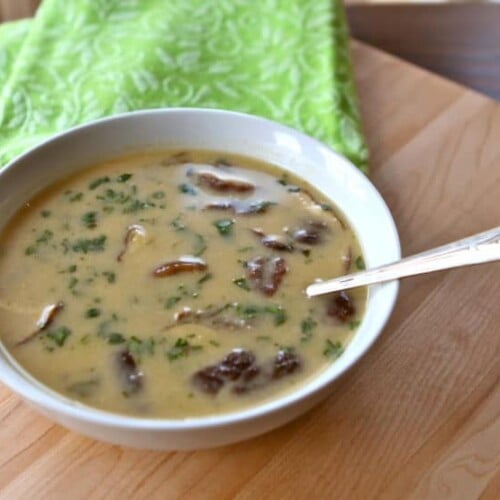 A bowl of coconut soup with red curry paste, coconut milk, and chicken, served with spoon