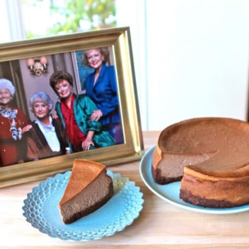 A delicious cheesecake and a slice of cheese cake on blue plates and a photo of the golden girls on a picture frame