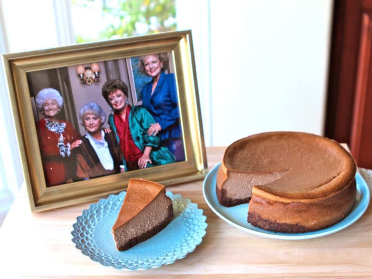 A delicious cheesecake and a slice of cheese cake on blue plates and a photo of the golden girls on a picture frame