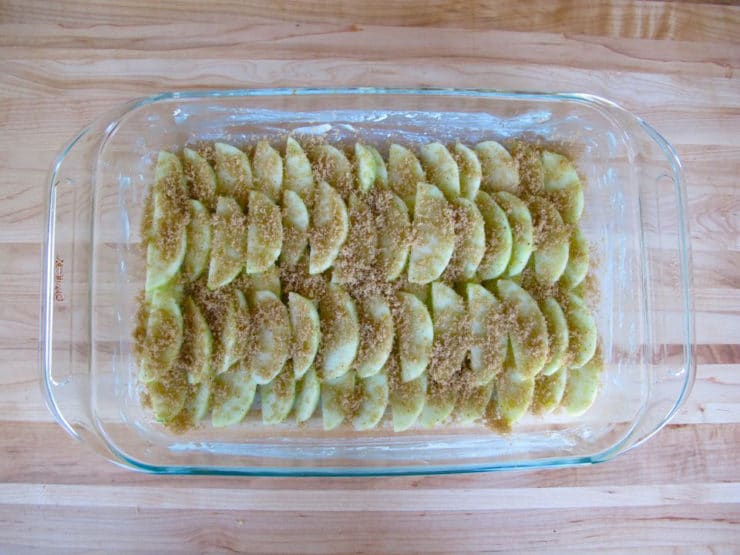Brown sugar over apples in a baking dish.