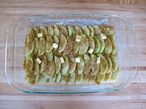 Butter dotted over apples in baking dish.