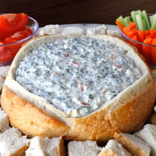 A bowl of Spinach Dip surrounded by bread and vegetables, ready to be enjoyed as a delicious appetizer