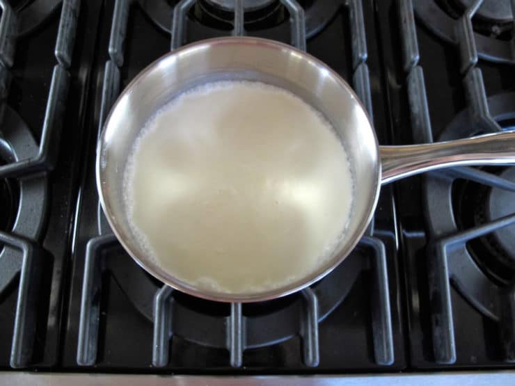 Heating heavy cream in a saucepan.