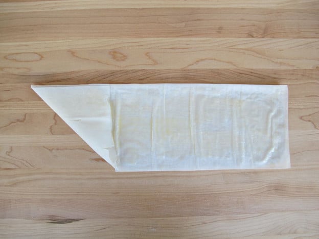 Begin folding rectangle up into triangle.