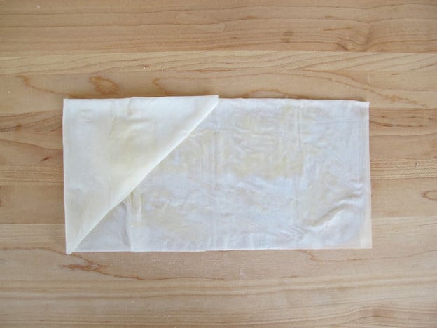 Begin folding rectangle up into triangle.