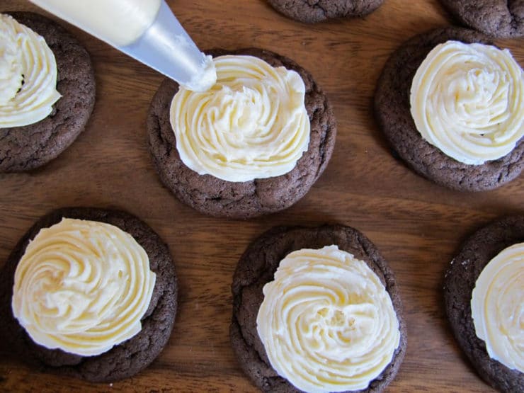 Piping frosting on mini cakes.