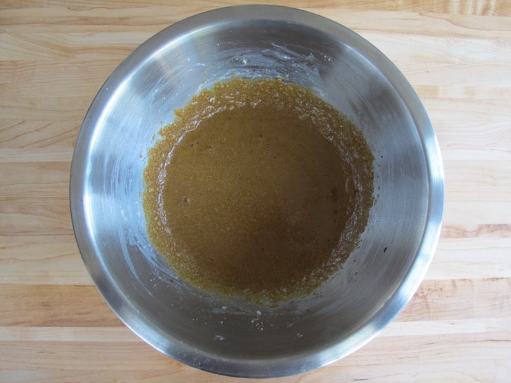 Molasses liquid batter in stainless steel bowl on wooden background.