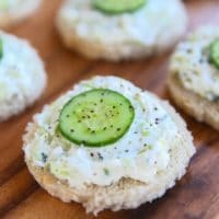 Cucumber rye open faced finger sandwich, crustless, with pepper on a wooden background.