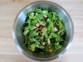 Fruit and lettuce tossed in a large bowl.