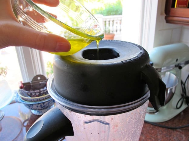 Drizzling oil into a running blender.