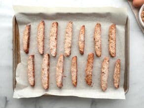Horizontal overhead shot of a baking sheet lined with parchment paper. Slices of mandel bread lay on top.