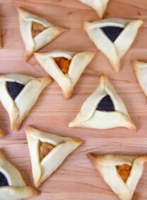Image of triangular buttery hamantaschen dough with yellow and dark purple filling.