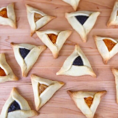 Image of triangular buttery hamantaschen dough with yellow and dark purple filling.